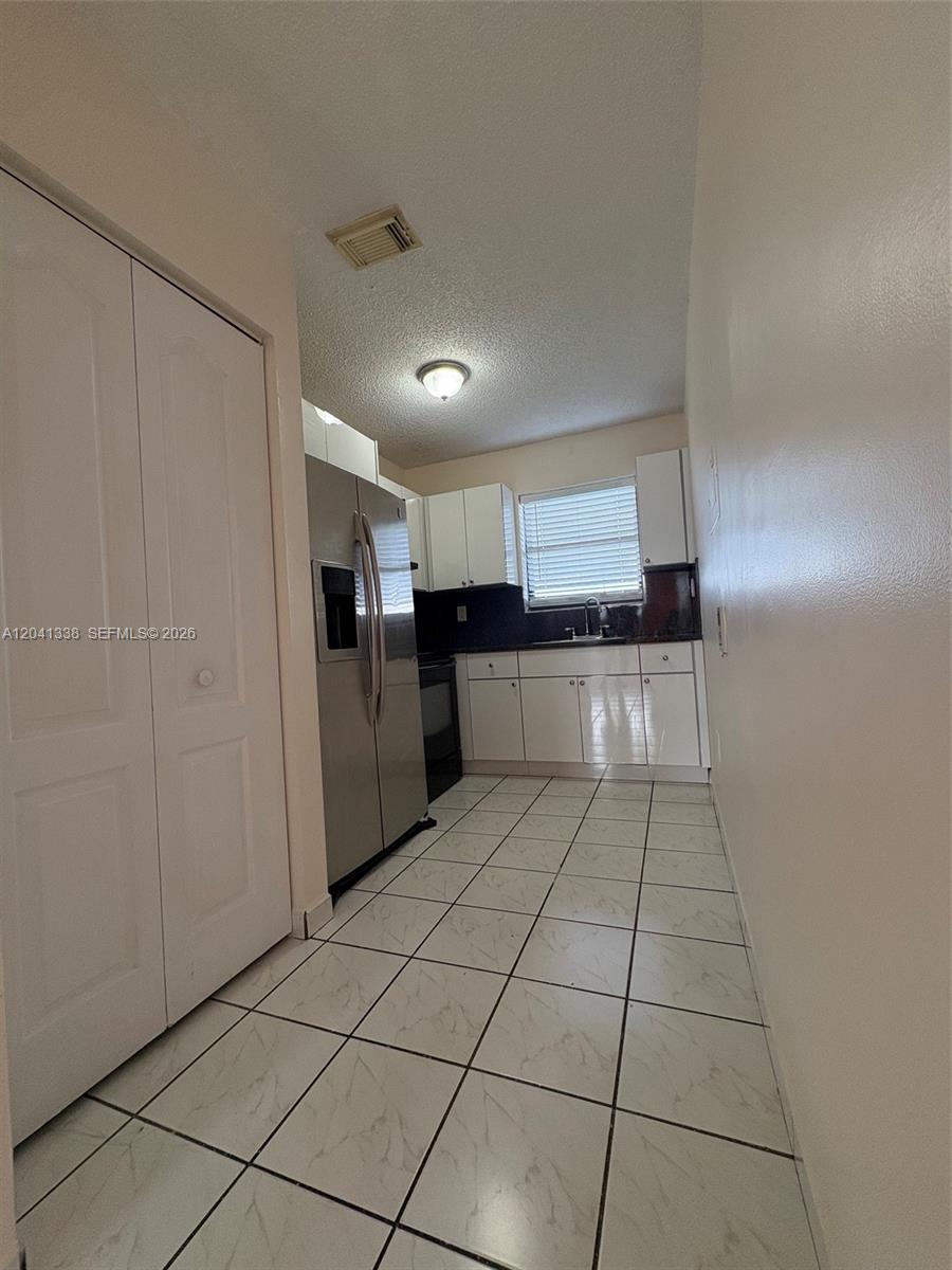 A long, white-walled room features light-colored tiled flooring and an open kitchen in the back — 231 E 7th St # 202, Hialeah FL 33010, HIALEAH, FL