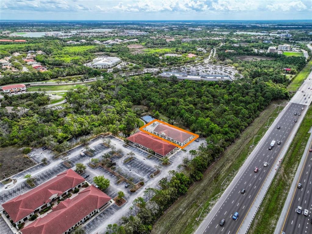 An aerial view shows a commercial building with a red roof surrounded by parking lots — 8946 77TH TERRACE E, LAKEWOOD RANCH, FL