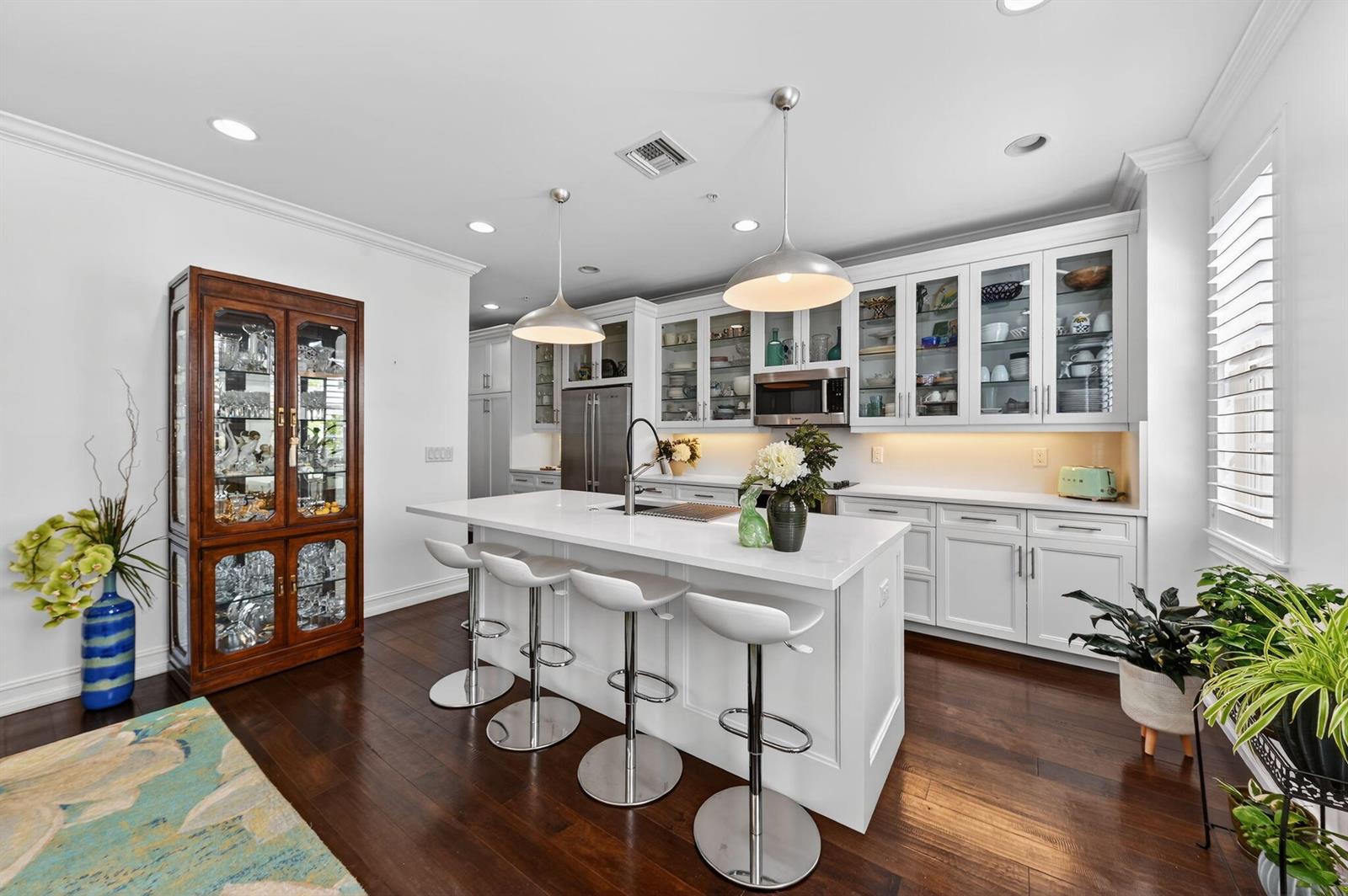 A modern kitchen features white cabinetry, a central island with bar stools, and hardwood floors — 145 N Cannery Row Circle, Delray Beach FL 33444, DELRAY BEACH, FL