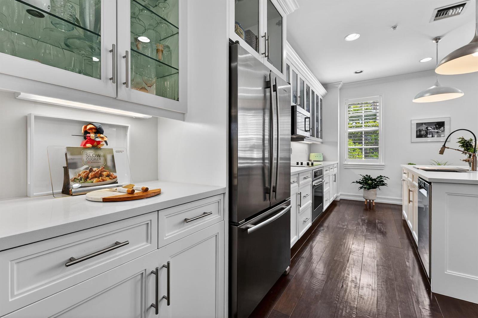 A modern kitchen features white cabinetry, stainless steel appliances, and dark hardwood flooring — 145 N Cannery Row Circle, Delray Beach FL 33444, DELRAY BEACH, FL