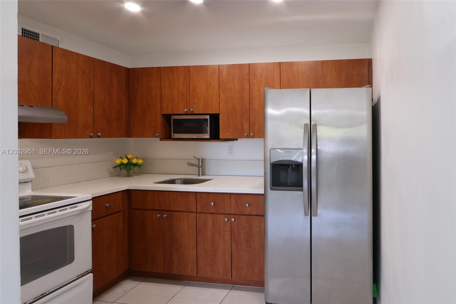 A kitchen features wood cabinets, white countertops, stainless steel appliances, and a white stove — 11195 SW 1st St # 119, Miami FL 33174, MIAMI, FL