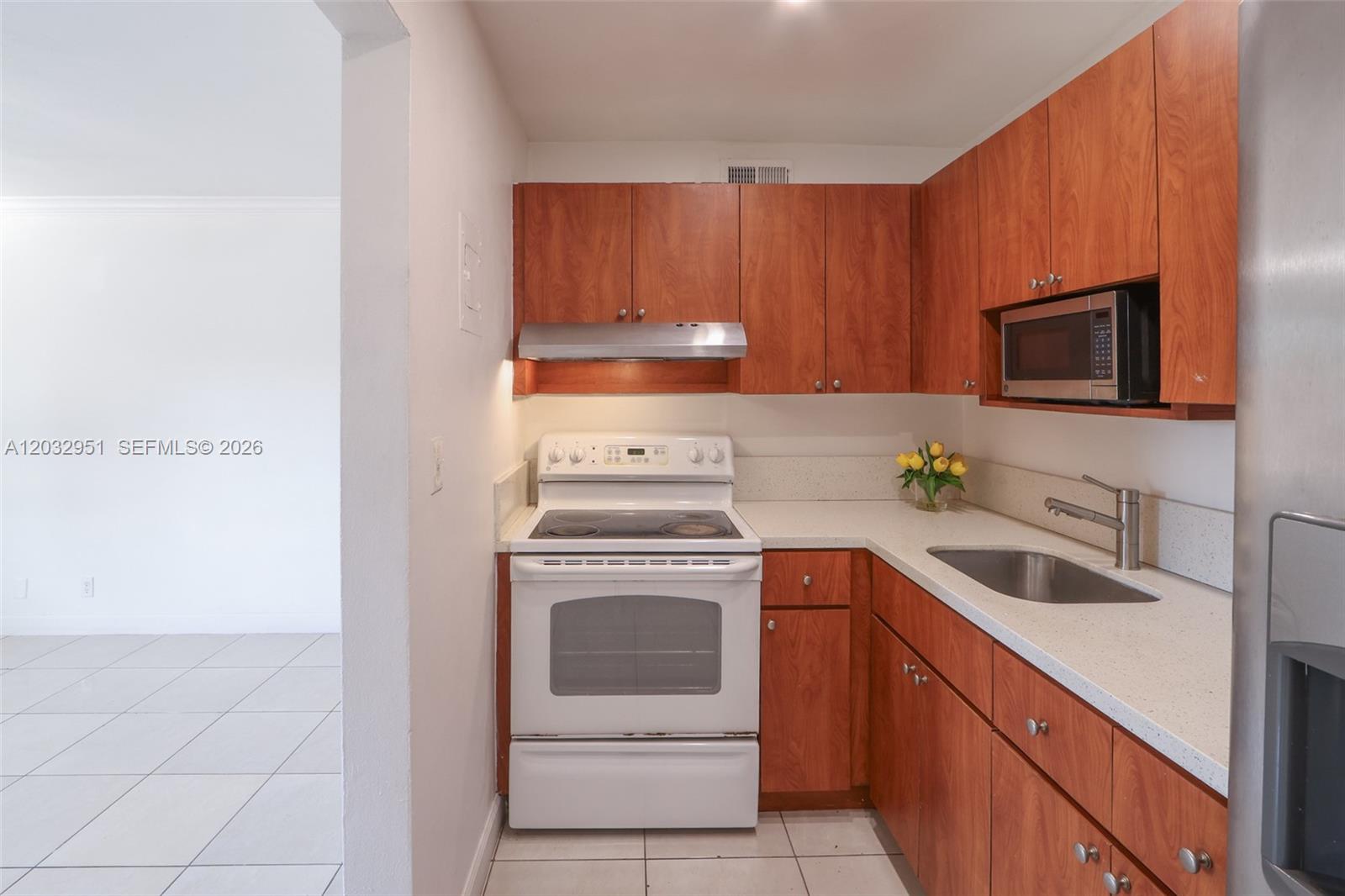 A kitchen features wood cabinets, white appliances, a stainless steel sink, and light countertops — 11195 SW 1st St # 119, Miami FL 33174, MIAMI, FL