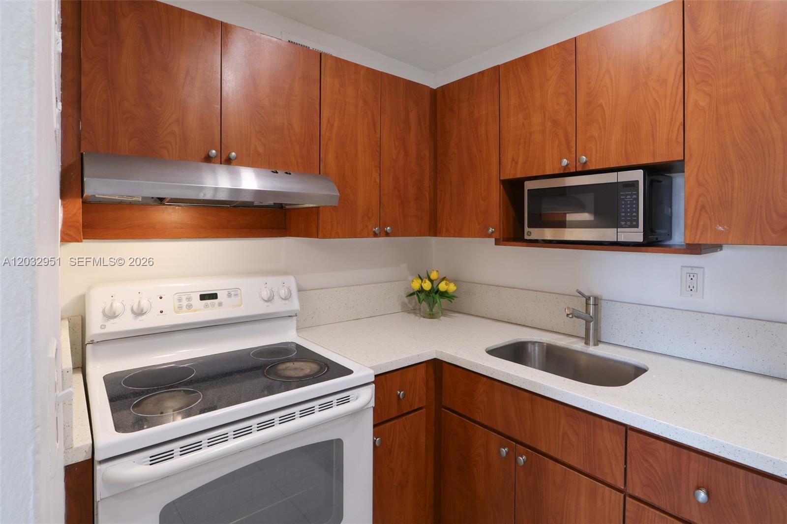 A kitchen features wood cabinets, white countertops, a white electric stove, and a stainless steel sink — 11195 SW 1st St # 119, Miami FL 33174, MIAMI, FL