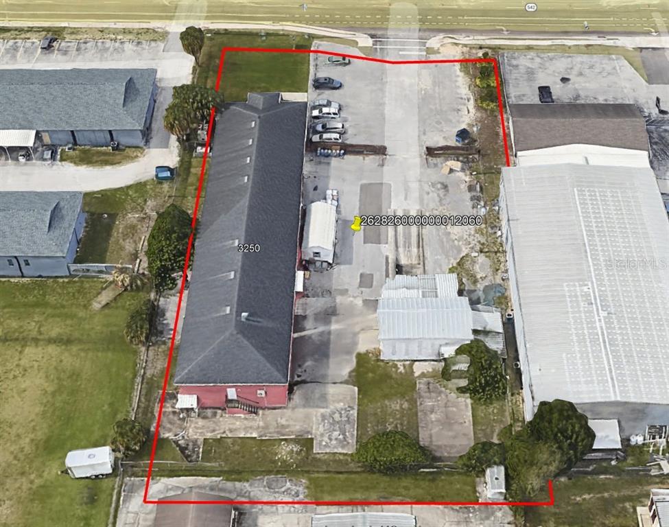 An aerial view shows a commercial property with a long building and a paved lot — 3250 DUNDEE ROAD, WINTER HAVEN, FL