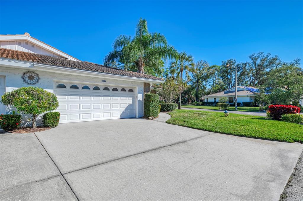 A white house with a two-car garage and a concrete driveway under a clear sky — 5711 GARDEN LAKES PALM, BRADENTON, FL
