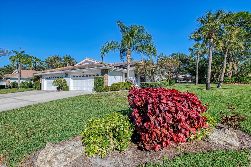 A single-story house with a white exterior, a two-car garage, and a landscaped front yard — 5711 GARDEN LAKES PALM, BRADENTON, FL