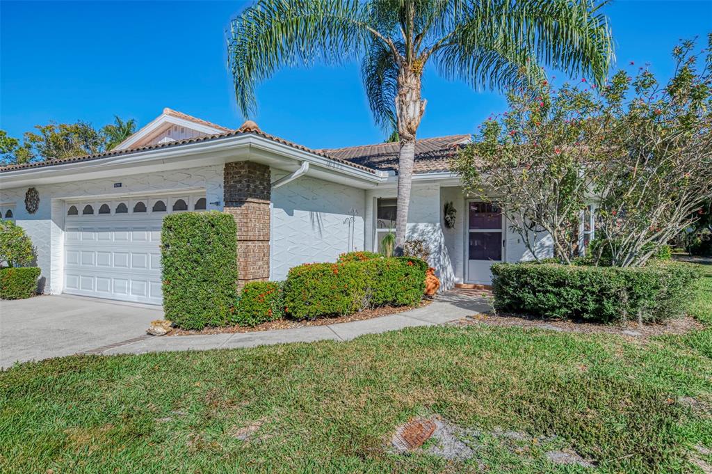 A single-story house with a white brick exterior, a two-car garage, and a palm tree — 5711 GARDEN LAKES PALM, BRADENTON, FL