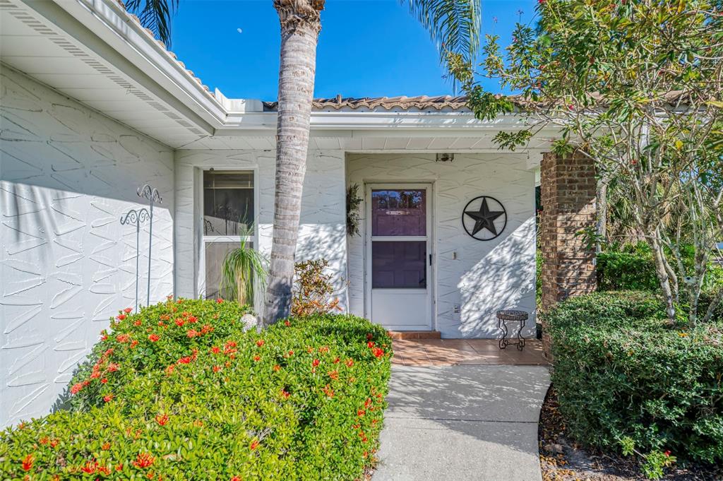 A white house exterior features a front door with a storm door and a star decoration — 5711 GARDEN LAKES PALM, BRADENTON, FL