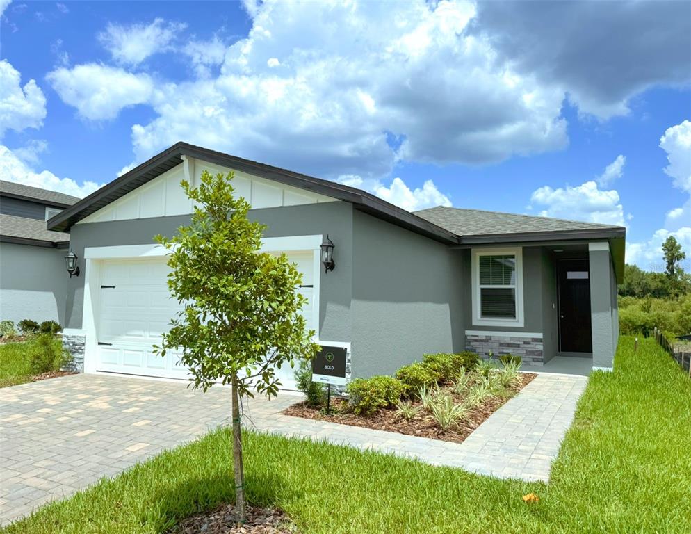 A single-story house with a gray exterior, white garage door, and a paved walkway — 1461 BREKEY WAY, ZEPHYRHILLS, FL