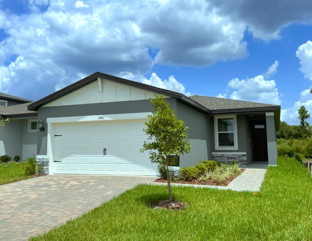 A single-story house with a gray exterior, white garage door, and a paved driveway — 1461 BREKEY WAY, ZEPHYRHILLS, FL