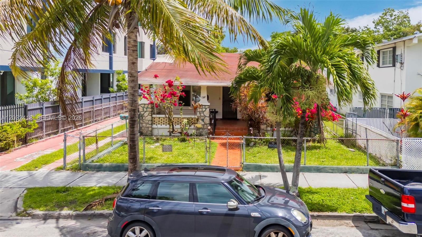 A single-story house with a stone porch and red roof sits behind a chain-link fence — 1243 SW 3rd St # 1, Miami FL 33135, MIAMI, FL