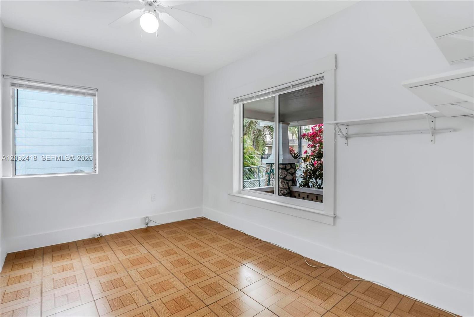 An empty room features light-colored walls, parquet flooring, a ceiling fan, and two windows — 1243 SW 3rd St # 1, Miami FL 33135, MIAMI, FL