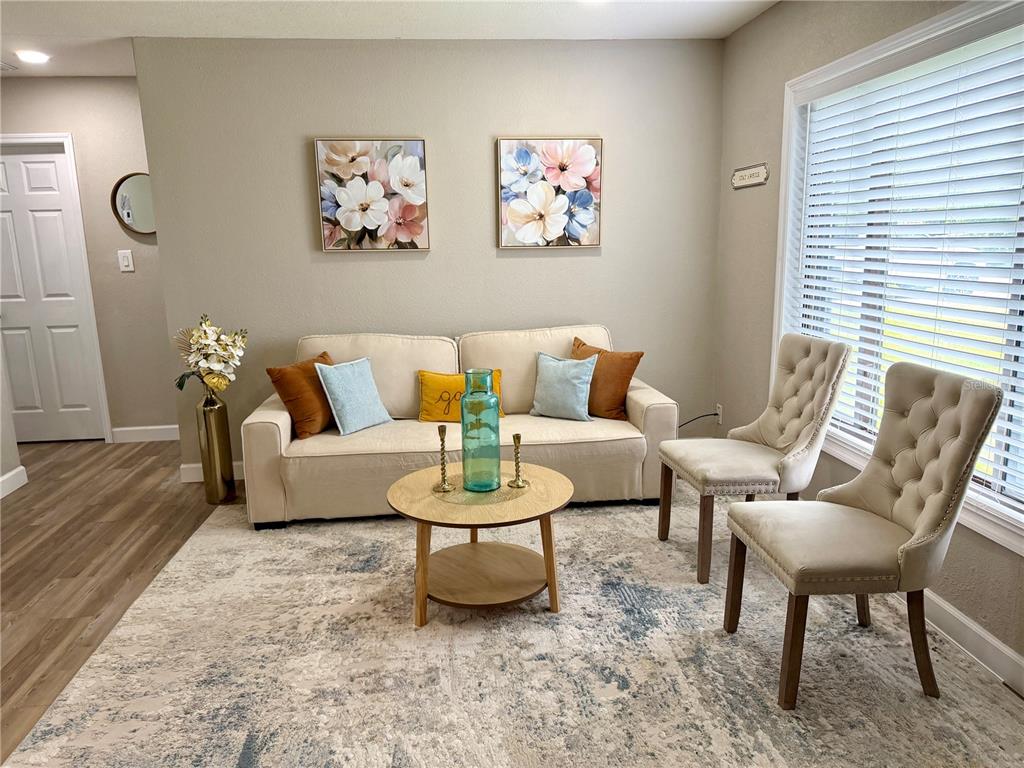 A living room features a beige sofa, two tufted chairs, a coffee table, and area rug — 6612 SIERRA TERRACE, NEW PORT RICHEY, FL