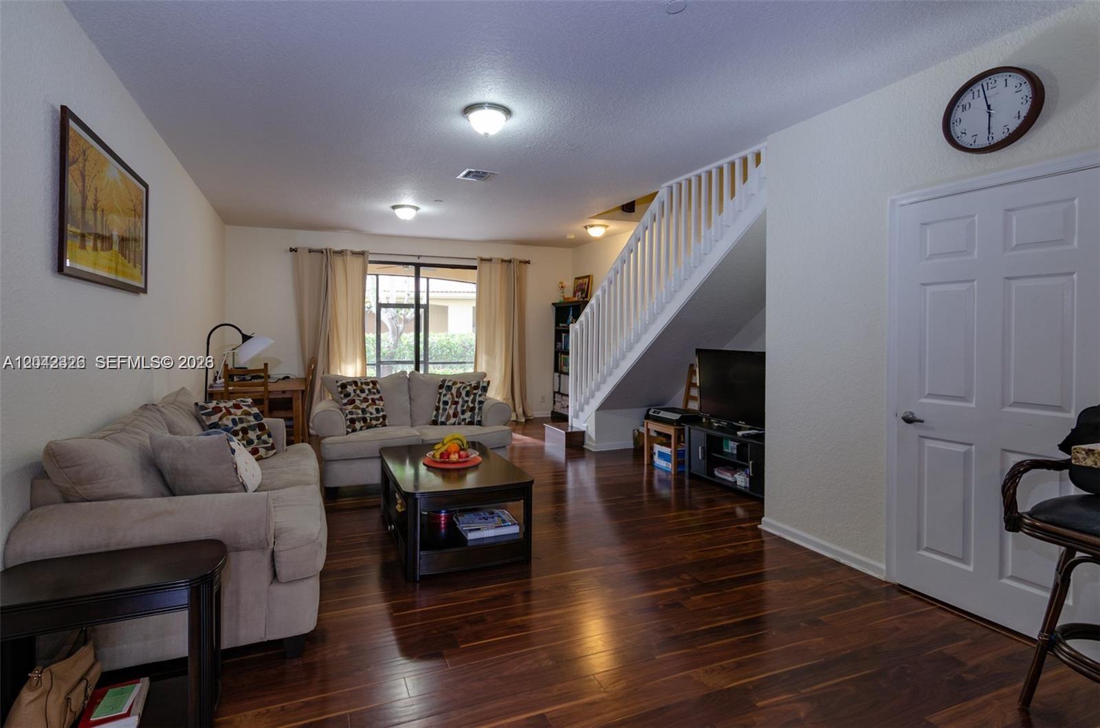 A living room features hardwood floors, a staircase, a sofa, and a television under the stairs — 4309 Vineyard Cir # 4309, Weston FL 33332, WESTON, FL