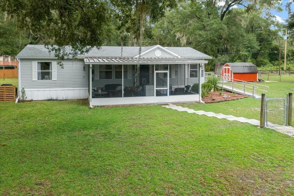 A single-story house with light gray siding and a large screened-in front porch — 15701 NE 150TH AVENUE, FORT MC COY, FL