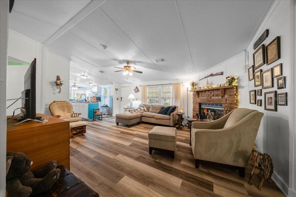 A living room with wood-look flooring, a stone fireplace, and a sectional sofa — 15701 NE 150TH AVENUE, FORT MC COY, FL
