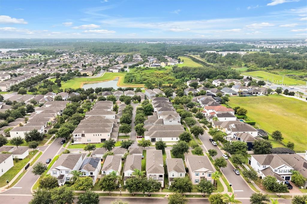 An aerial view shows a suburban neighborhood with rows of houses, streets, and a pond — 14699 MAGNOLIA RIDGE LOOP, WINTER GARDEN, FL