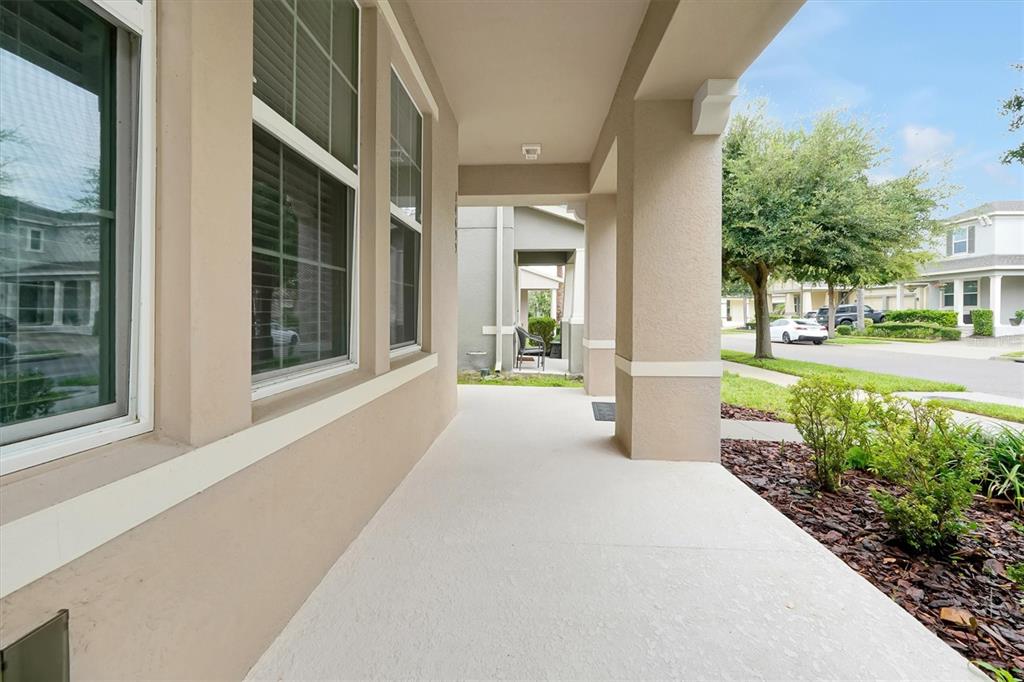A covered concrete porch with beige walls and columns overlooks a suburban street — 14699 MAGNOLIA RIDGE LOOP, WINTER GARDEN, FL