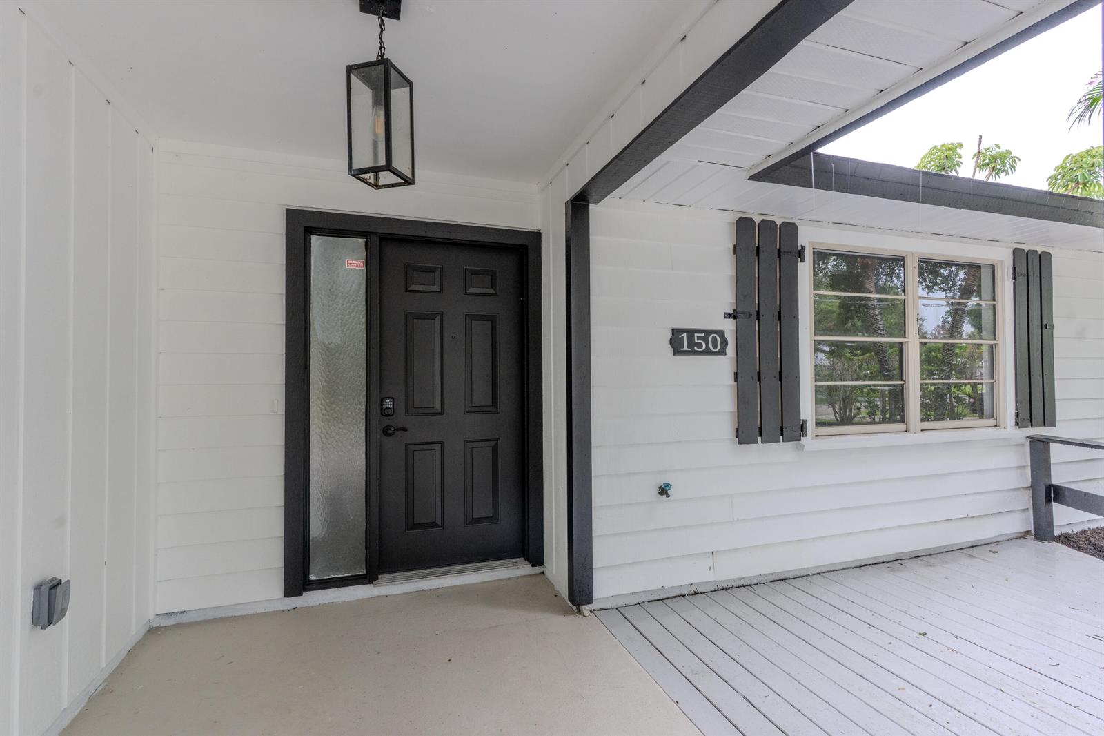 A white house exterior features a black front door, a porch, and a window — 150 23rd Avenue, Vero Beach FL 32962, VERO BEACH, FL