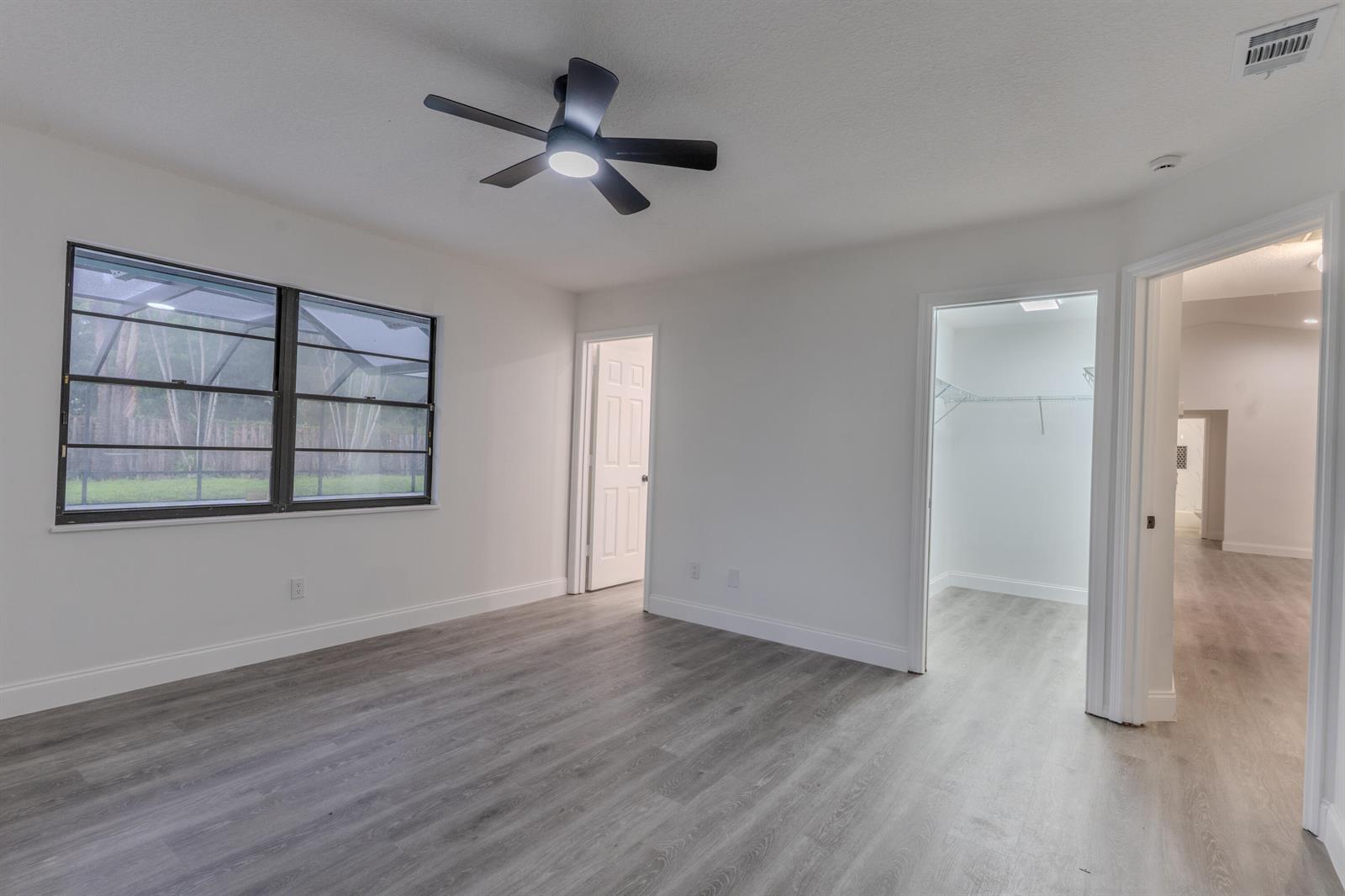 An empty bedroom features light gray wood-look flooring, white walls, a ceiling fan, and two doorways — 150 23rd Avenue, Vero Beach FL 32962, VERO BEACH, FL