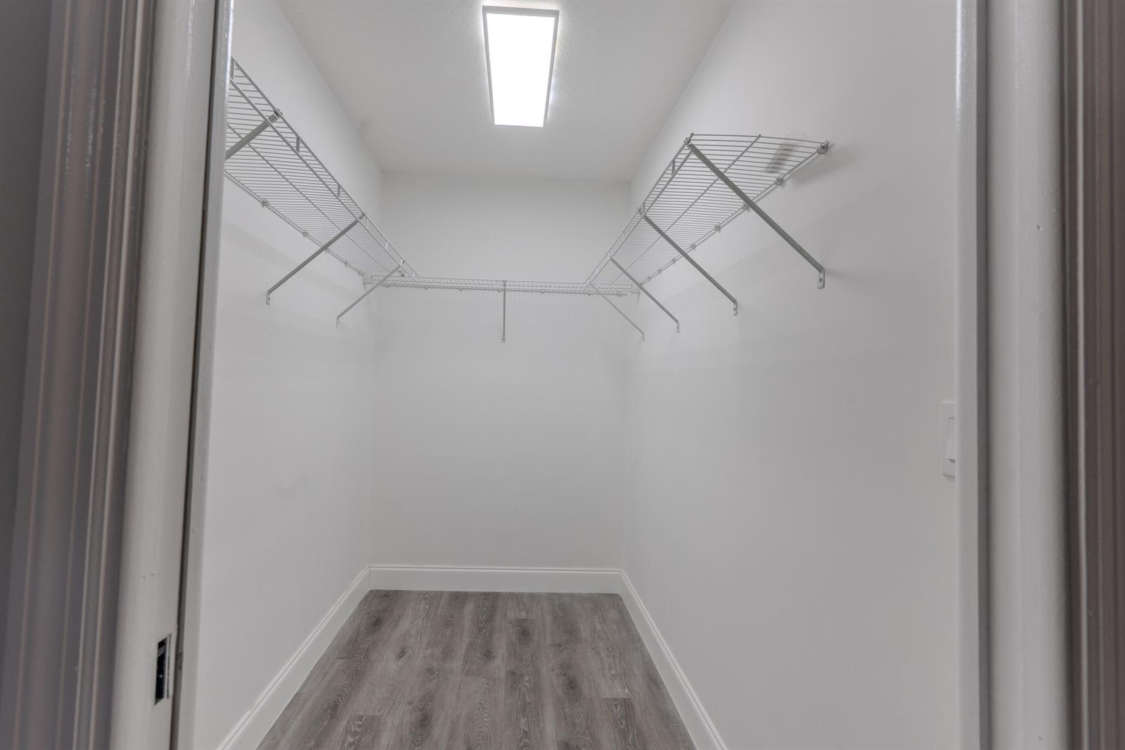 A walk-in closet features white walls, wire shelving, and wood-look flooring — 150 23rd Avenue, Vero Beach FL 32962, VERO BEACH, FL