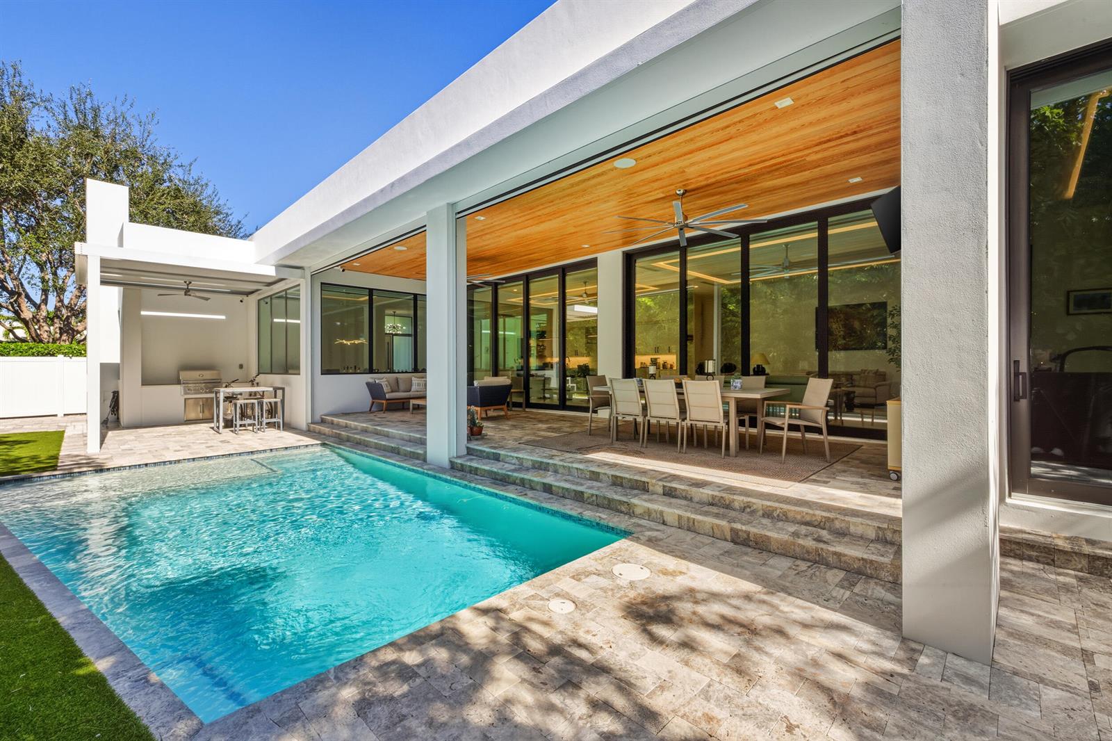 A modern patio with a swimming pool, outdoor dining area, and wood-paneled ceiling — 10 Coconut Road, Delray Beach FL 33444, DELRAY BEACH, FL