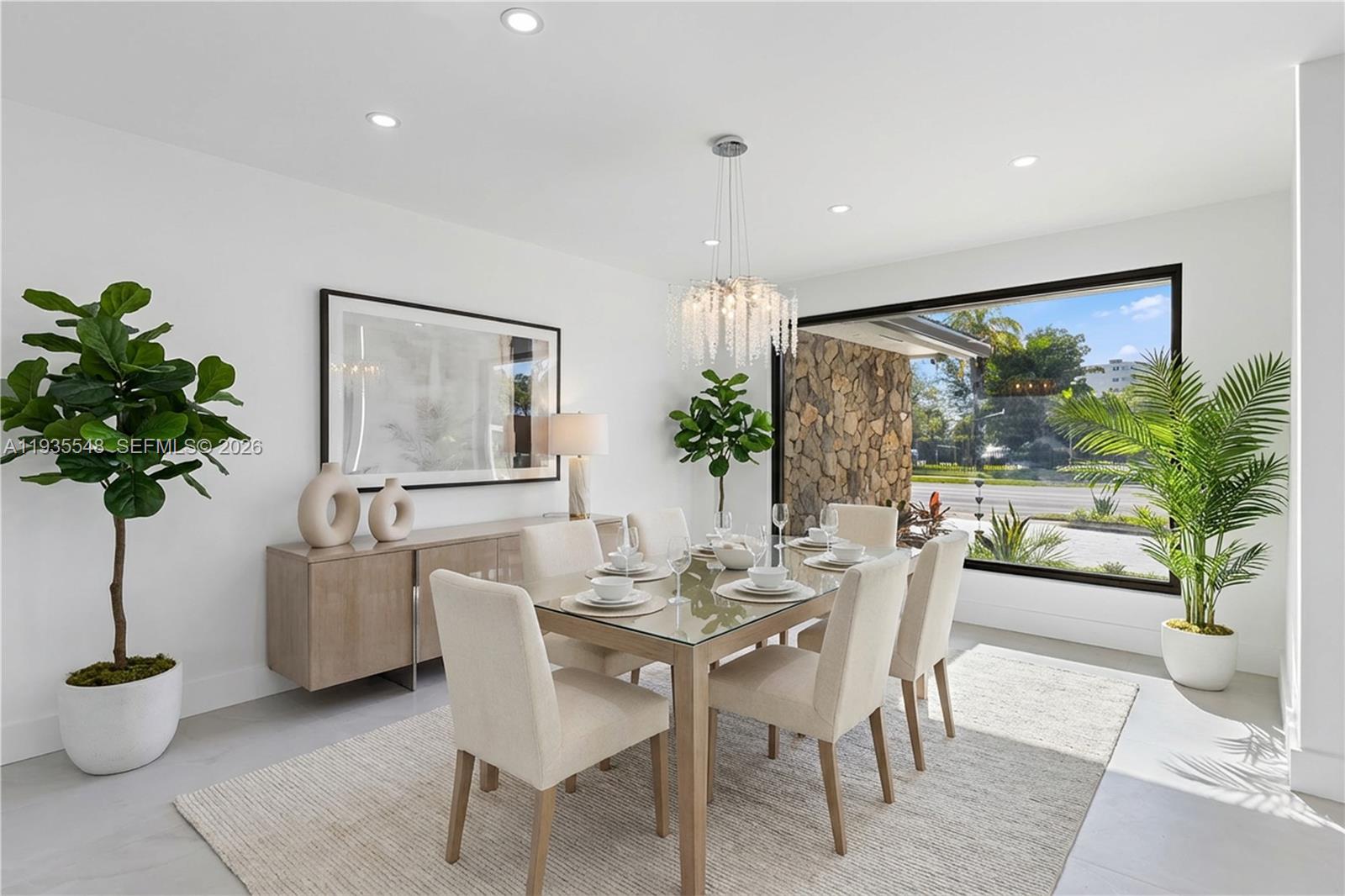 A modern dining room features a glass table, upholstered chairs, a sideboard, and large windows — 18735 NE 18th Ave, Miami FL 33179, MIAMI, FL