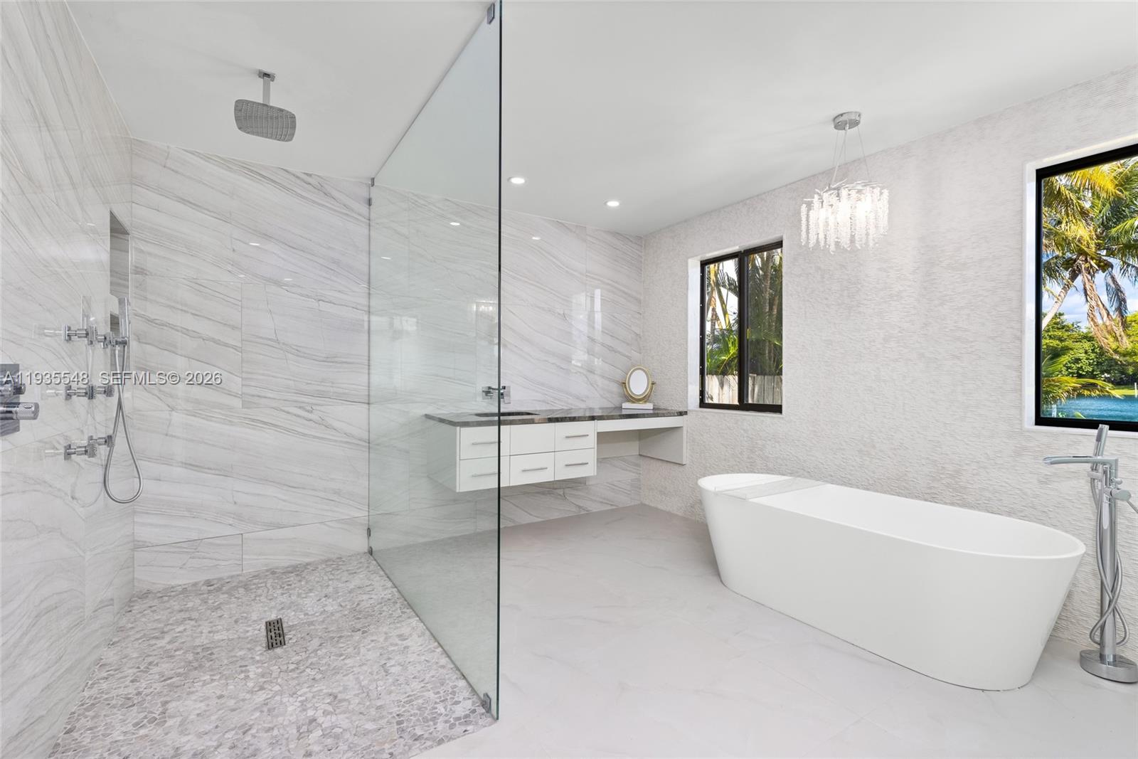 A modern bathroom features a glass-enclosed shower, a freestanding tub, and a floating vanity — 18735 NE 18th Ave, Miami FL 33179, MIAMI, FL