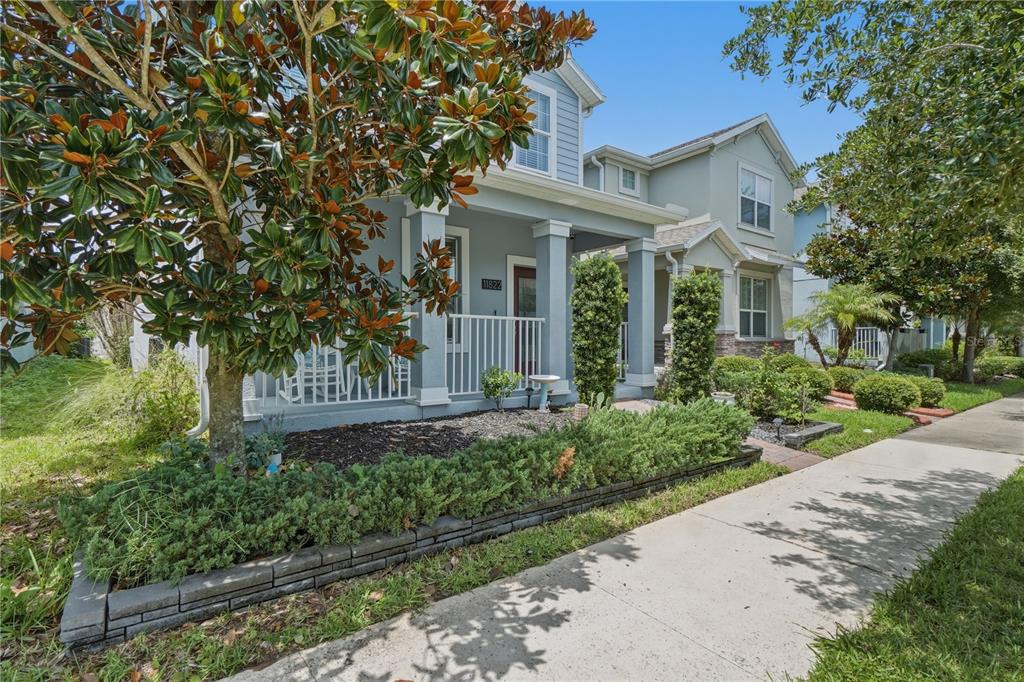 A blue two-story house with a front porch, landscaping, and a sidewalk in the foreground — 11822 PHILOSOPHY WAY, ORLANDO, FL