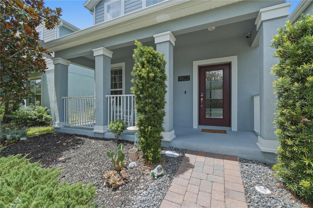 A front porch with a red door, white railings, and stone walkway leads to a house — 11822 PHILOSOPHY WAY, ORLANDO, FL
