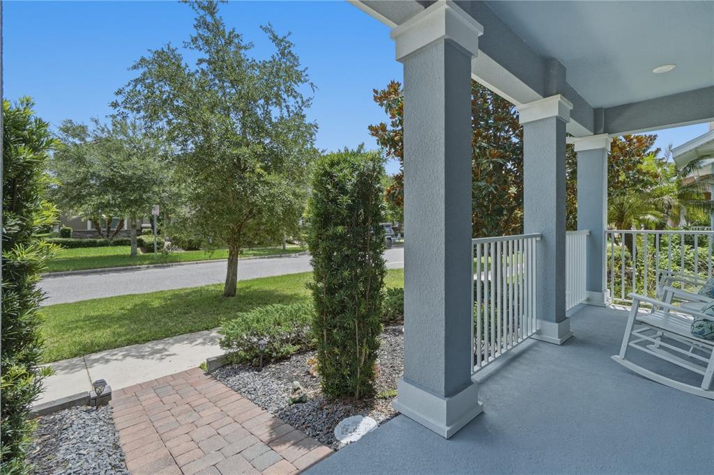 A covered front porch with blue flooring, white railings, and a brick walkway — 11822 PHILOSOPHY WAY, ORLANDO, FL