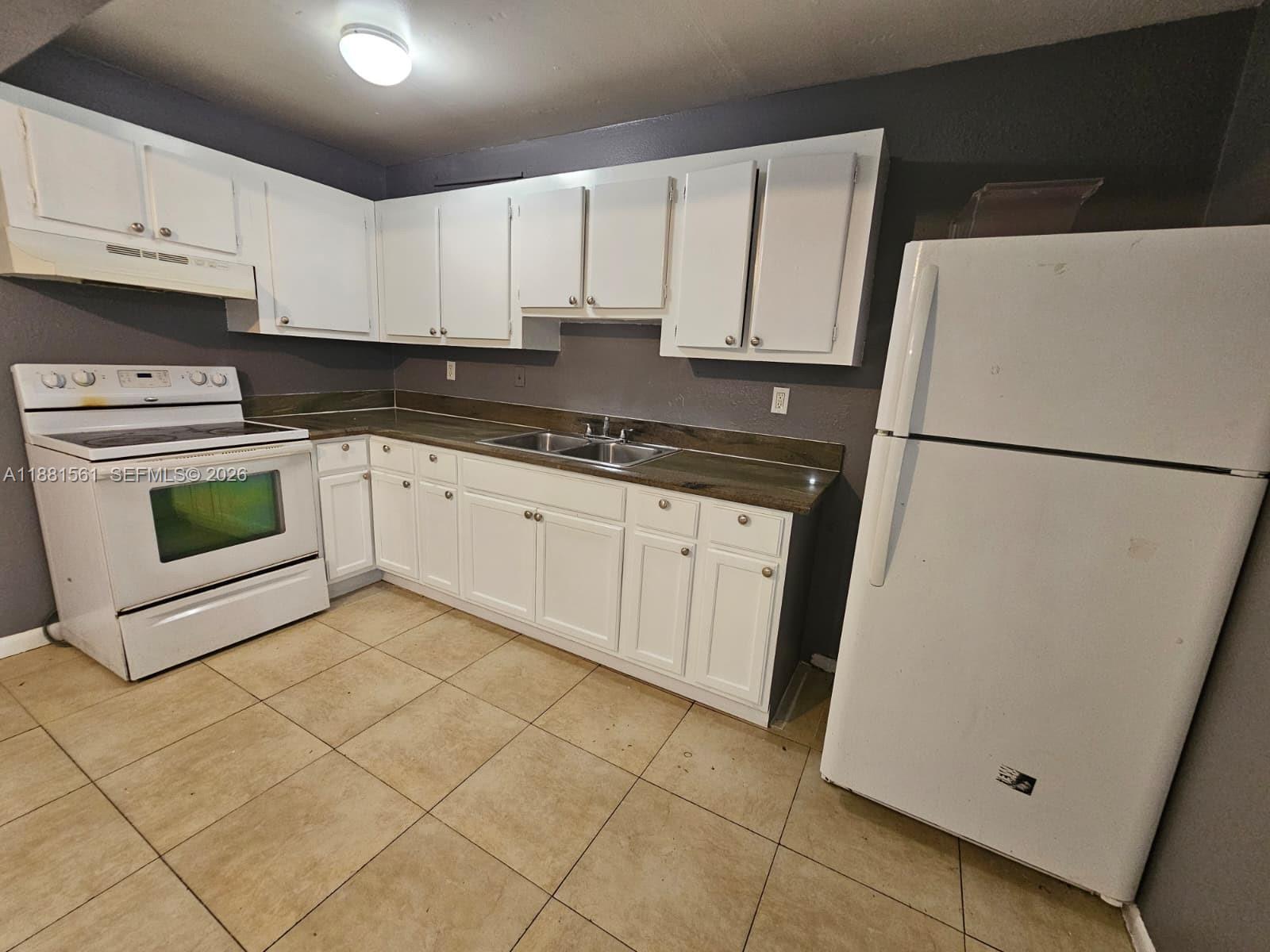 A kitchen features white cabinets, dark countertops, a white stove, and a white refrigerator — 325 SW 80th Ter, North Lauderdale FL 33068, NORTH LAUDERDALE, FL