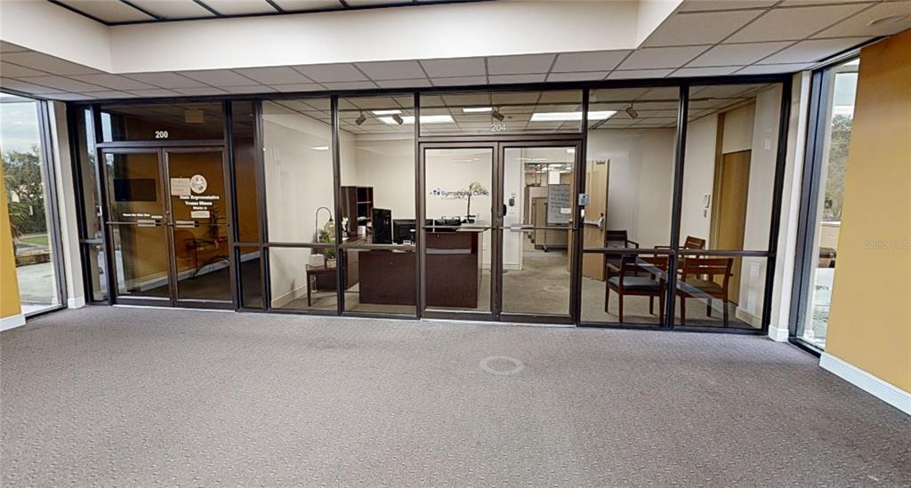 A commercial office suite features glass-walled partitions, carpeted flooring, and a reception area — 2815 NW 13TH STREET 2nd Floor, GAINESVILLE, FL