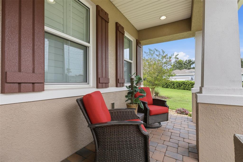 A covered porch features two wicker chairs with red cushions and a paved floor — 253 OLD MOSS CIRCLE, DELAND, FL