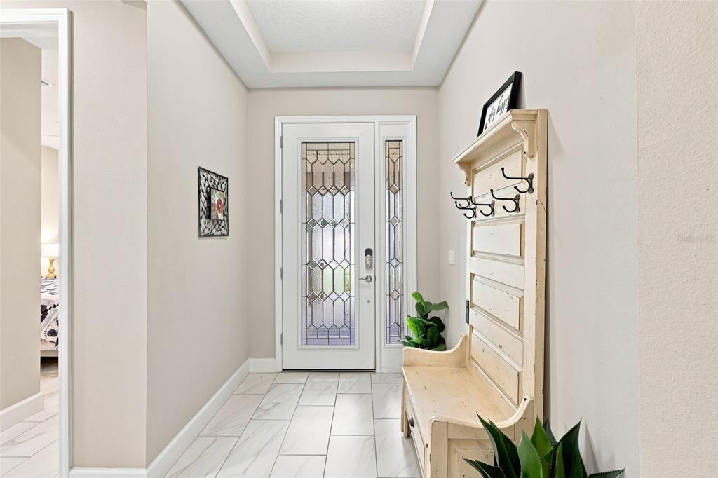 A bright entryway features a white front door with decorative glass, tile flooring, and furniture — 253 OLD MOSS CIRCLE, DELAND, FL