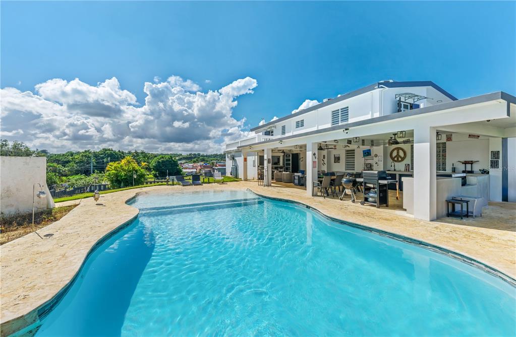 A swimming pool sits in front of a white two-story house with a covered patio — 1 PINAR DEL MAR STREET, CAMUY, PR