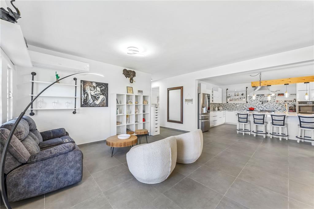 A living room with gray tile floors opens into a white kitchen with bar seating — 1 PINAR DEL MAR STREET, CAMUY, PR