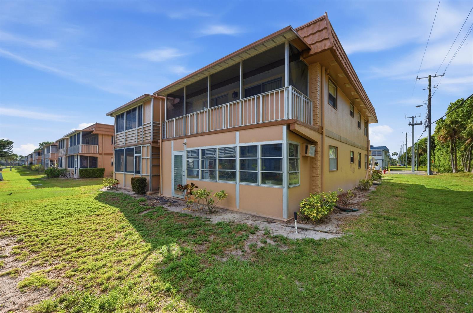 A two-story tan apartment building with screened balconies and a grassy yard — 336 Brittany G, Delray Beach FL 33446, DELRAY BEACH, FL
