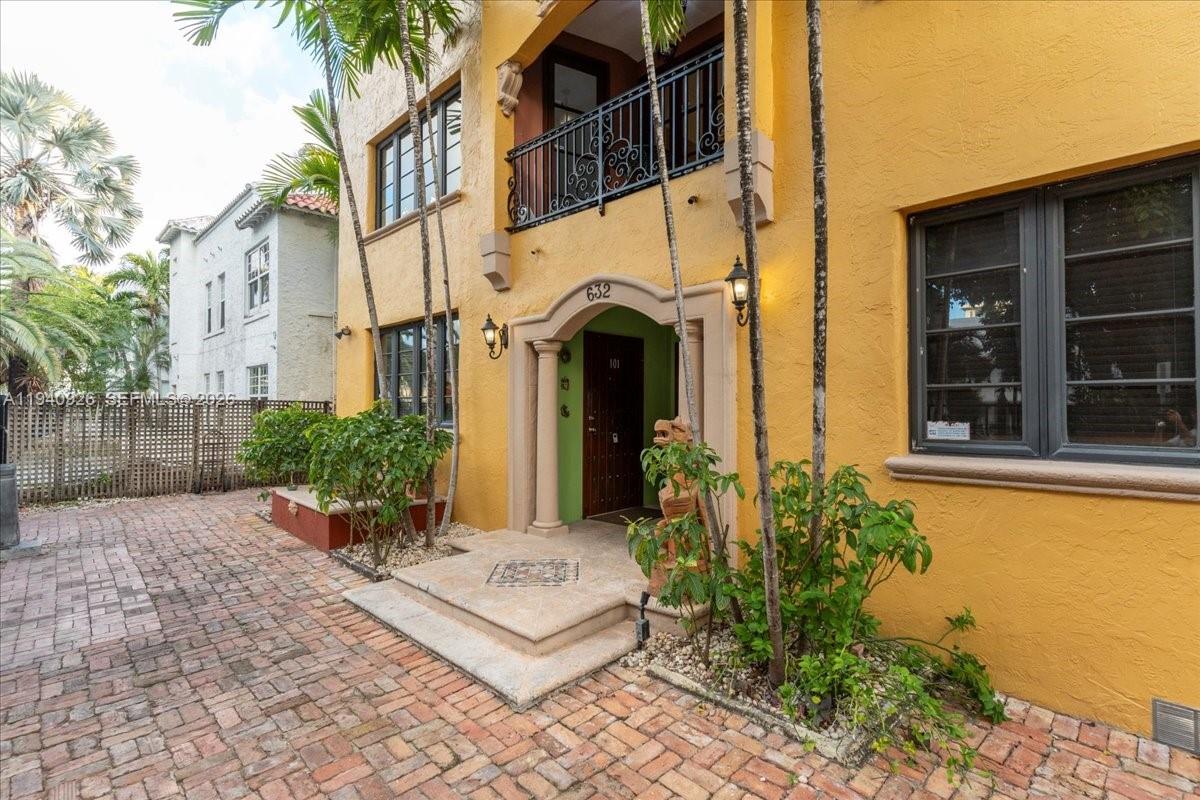A yellow stucco building exterior features a brick courtyard, arched entryway, and a wrought-iron balcony — 632 15th St, Miami Beach FL 33139, MIAMI BEACH, FL