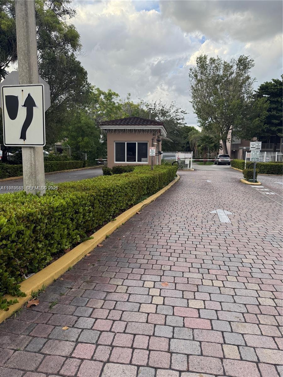 A gated entrance features a guardhouse, a paved driveway, and manicured hedges — 8405 NW 8th St # 304, Miami FL 33126, MIAMI, FL