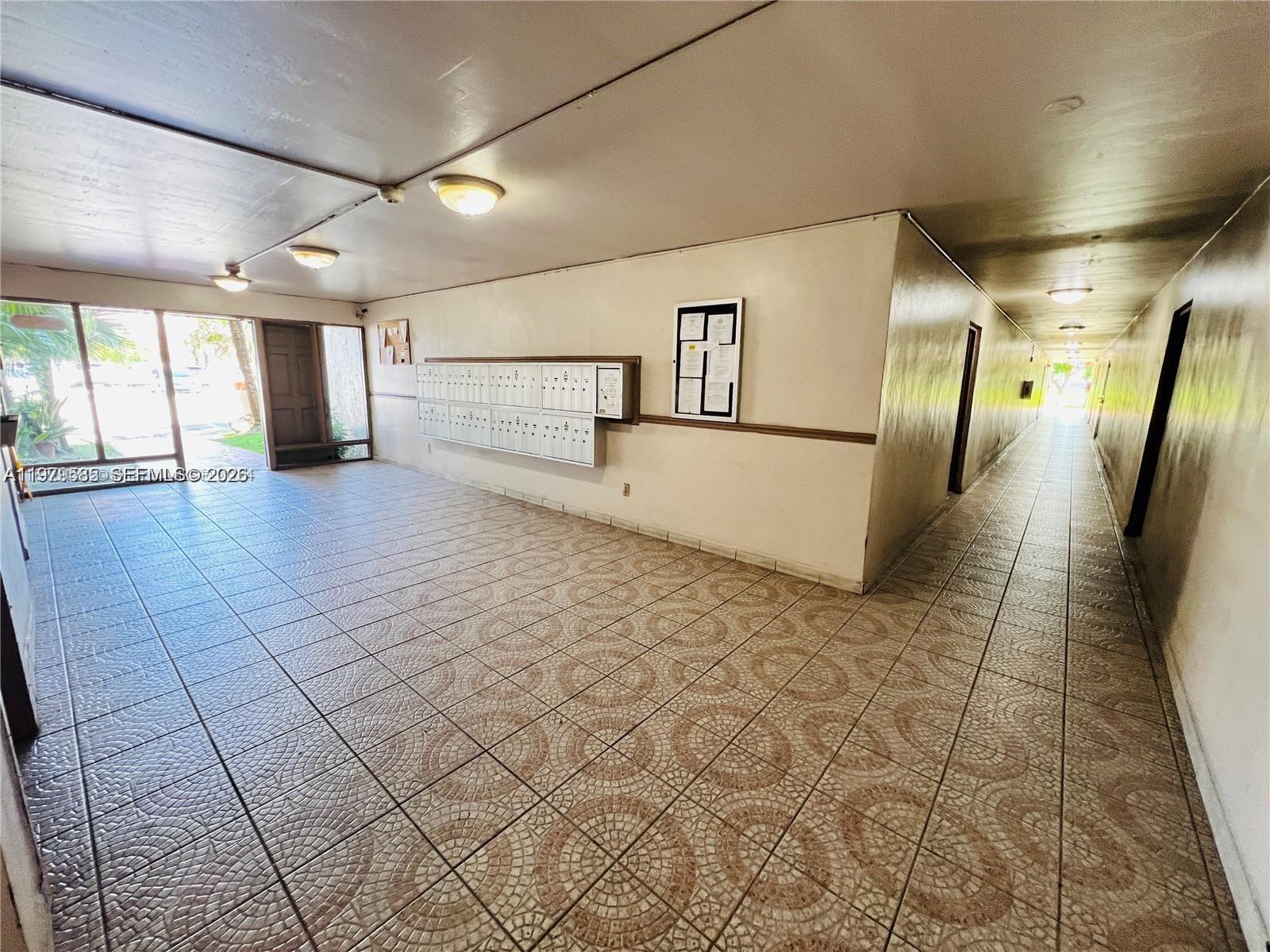 An apartment building lobby features tiled floors, a wall of mailboxes, and a long hallway — 8405 NW 8th St # 304, Miami FL 33126, MIAMI, FL