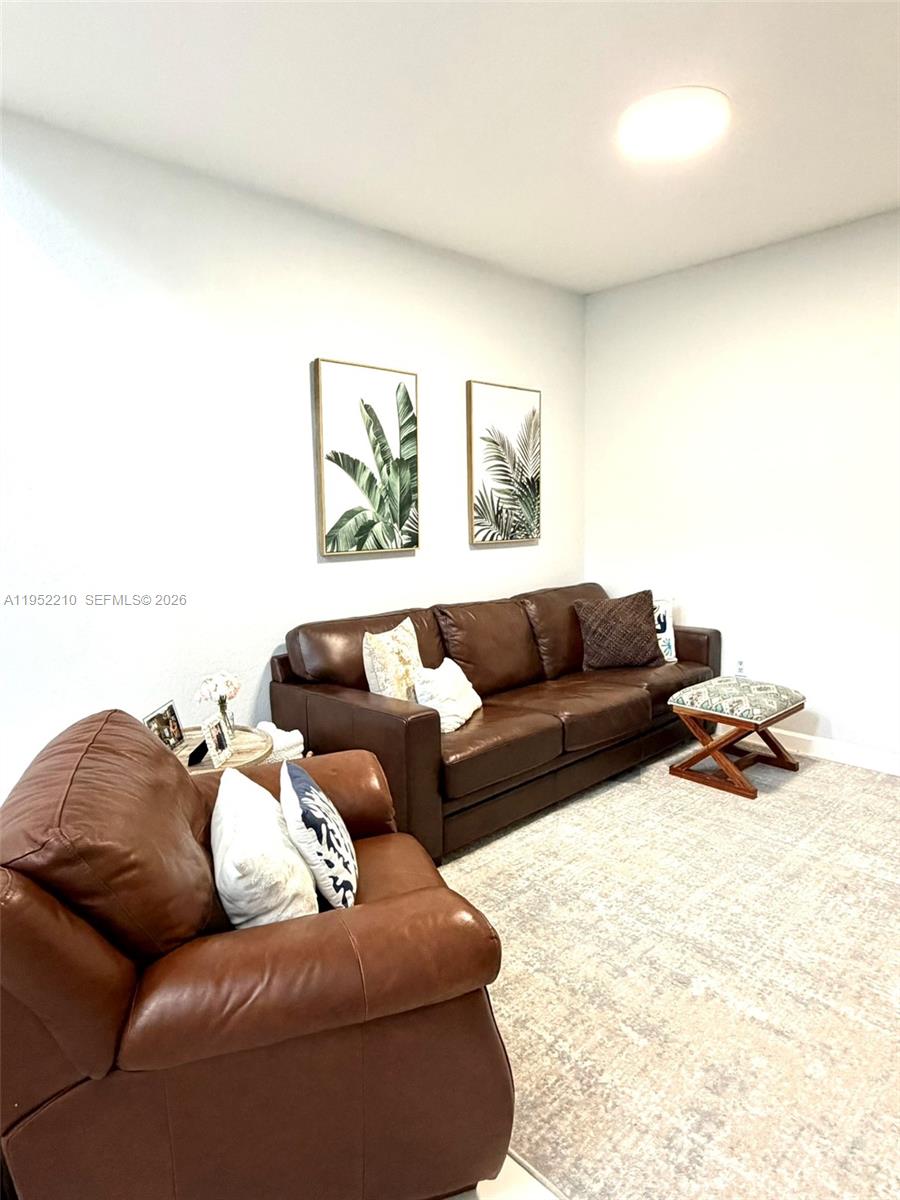 A living room features brown leather furniture, a patterned rug, and two framed botanical prints — 10780 NW 74th Ln, Doral FL 33178, DORAL, FL