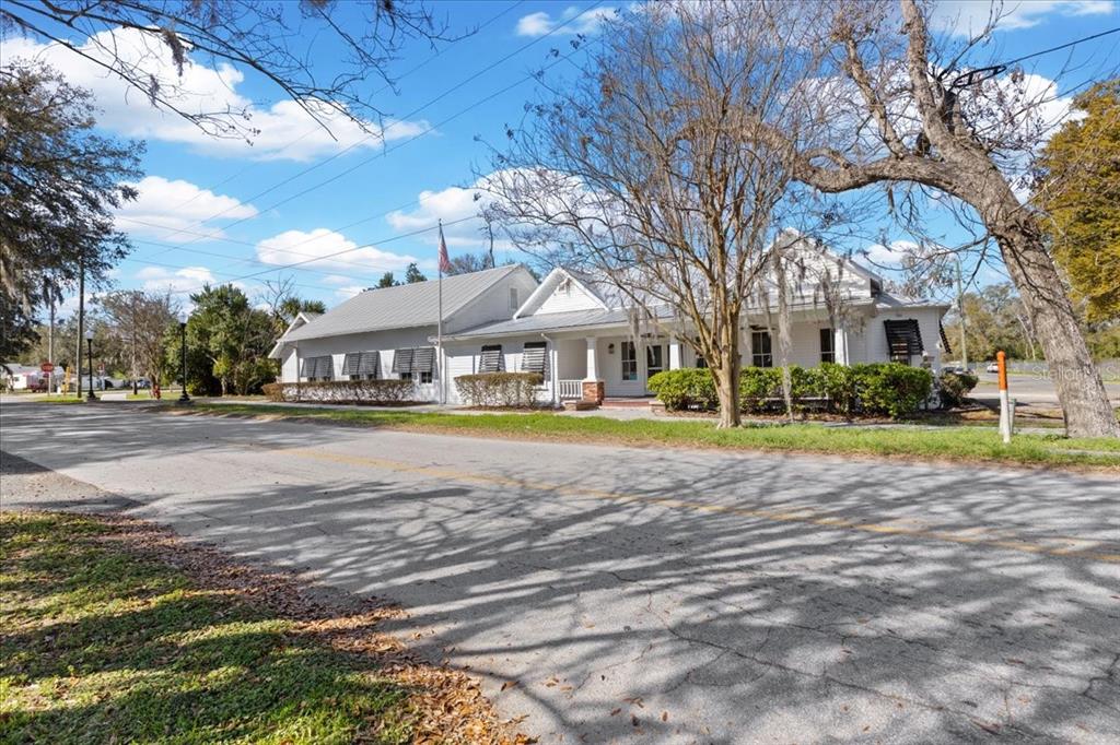A white, single-story building with a metal roof sits along a paved road — 115 NW 1ST STREET, TRENTON, FL