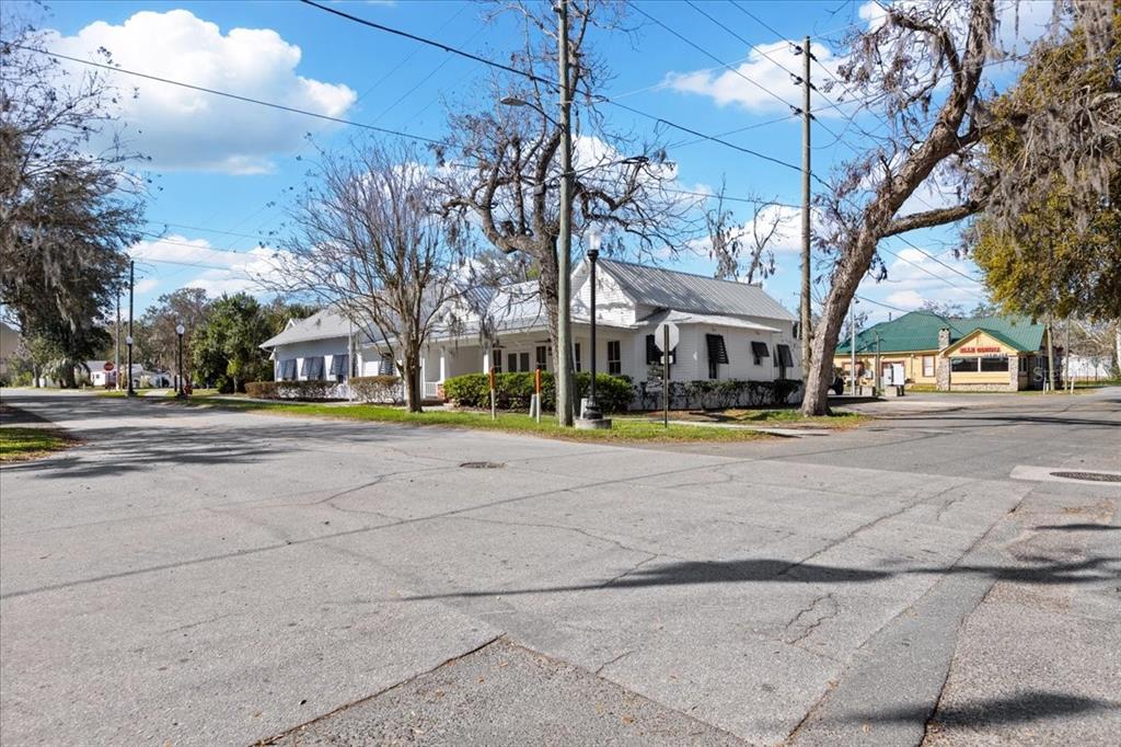 A white building with a metal roof sits on a corner lot near trees — 115 NW 1ST STREET, TRENTON, FL