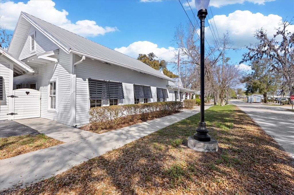 A white wooden building with a metal roof sits beside a sidewalk and street — 115 NW 1ST STREET, TRENTON, FL