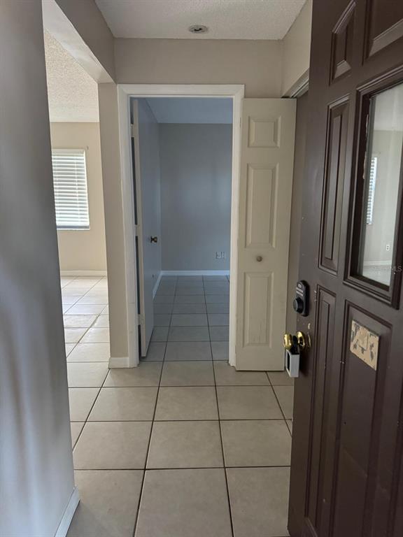 An entryway with light-colored floor tiles leads to a hallway and an adjacent room — 2416 SE GARDEN TERRACE UNIT 203, PORT ST LUCIE, FL