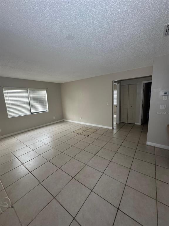 An empty room with light-colored tile flooring, beige walls, and a window with blinds — 2416 SE GARDEN TERRACE UNIT 203, PORT ST LUCIE, FL