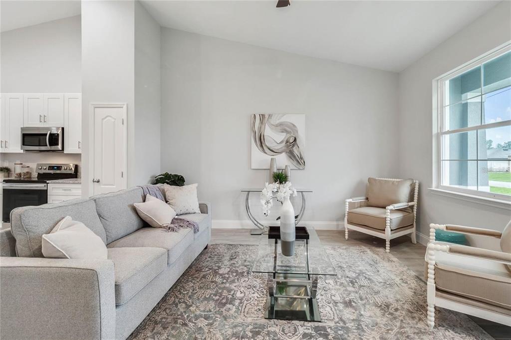 A living room features a gray sofa, two armchairs, a glass coffee table, and artwork — 2239 PECOS COURT, KISSIMMEE, FL