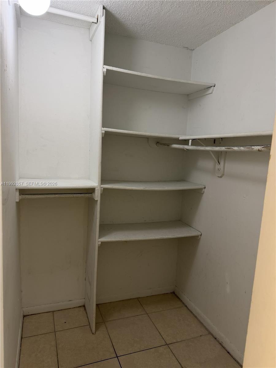 A walk-in closet features white shelving, a hanging rod, and tiled flooring — 7010 NW 186th St # 121A, Hialeah FL 33015, HIALEAH, FL