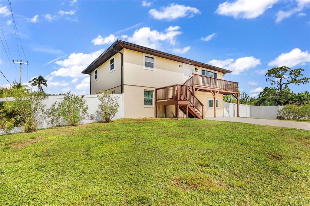 A two-story house with a wooden deck and staircase stands on a grassy lot — 3129 BANYAN WAY, PUNTA GORDA, FL